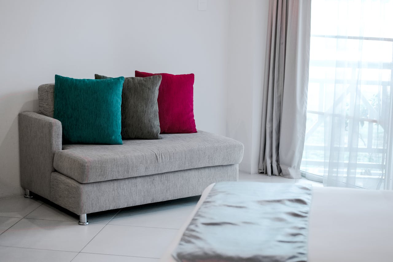 creative-03 Simple modern interior featuring a grey sofa with vibrant colored cushions in a bright room.