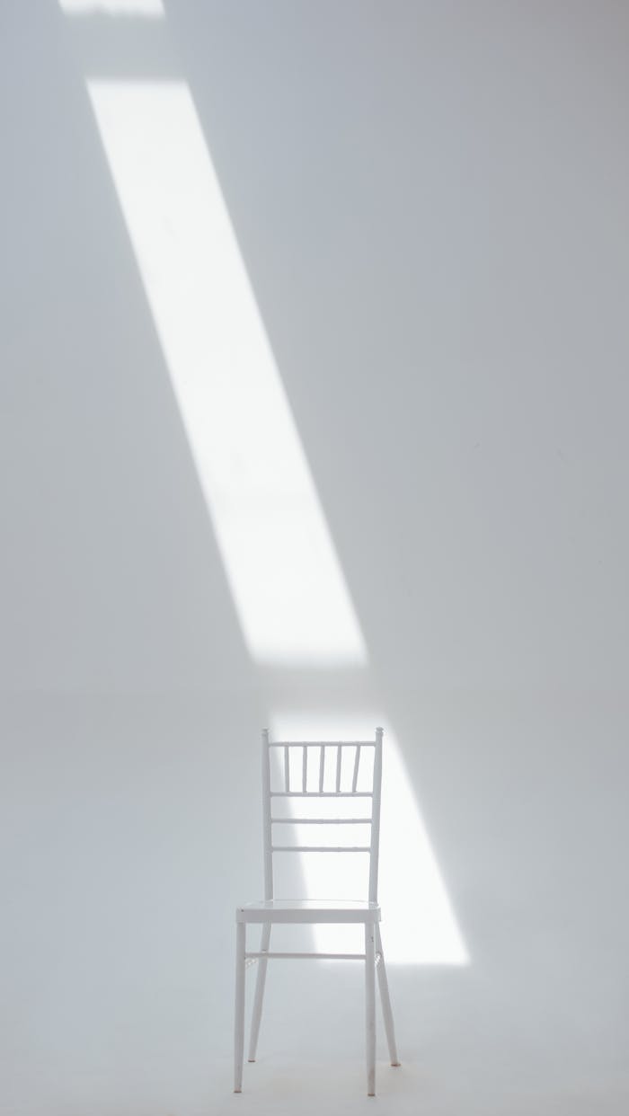 creative-02 A white chair in a minimalistic setting with sunlight casting a dramatic shadow.